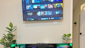 Televisor de pantalla plana montado en la pared que muestra diferentes servicios de streaming y películas.