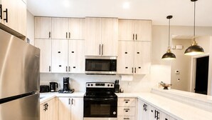 A modern kitchen with light wood cabinets, stainless steel appliances, and pendant lighting. - Beautiful 3-Beds Apartment in Mission with WIFI; Safe & Spacious Stay (Mission)