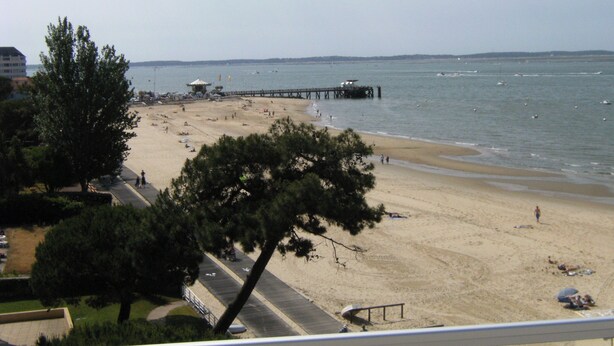 A beach with a pier extending into the water, surrounded by trees and buildings. - ARCACHON Eyrac Front de mer Apartment 68M2 with large balcony (Arcachon)