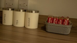 Tres recipientes etiquetados en una encimera: café, té y azúcar.