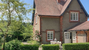 Uma casa tradicional com fachada de tijolos, telhado ladrilhado e um pequeno jardim com caminho de brita.