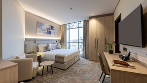 A modern hotel room with a large bed, a desk, a chair, and a TV. - Amriya Hotel (Madinah)