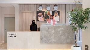 A reception desk with a marble top, a potted plant, and clocks on the wall. - Amriya Hotel (Madinah)