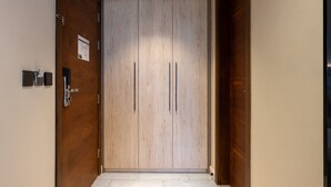 Un pasillo con un armario de madera, una puerta con manija y una lámpara en el techo.