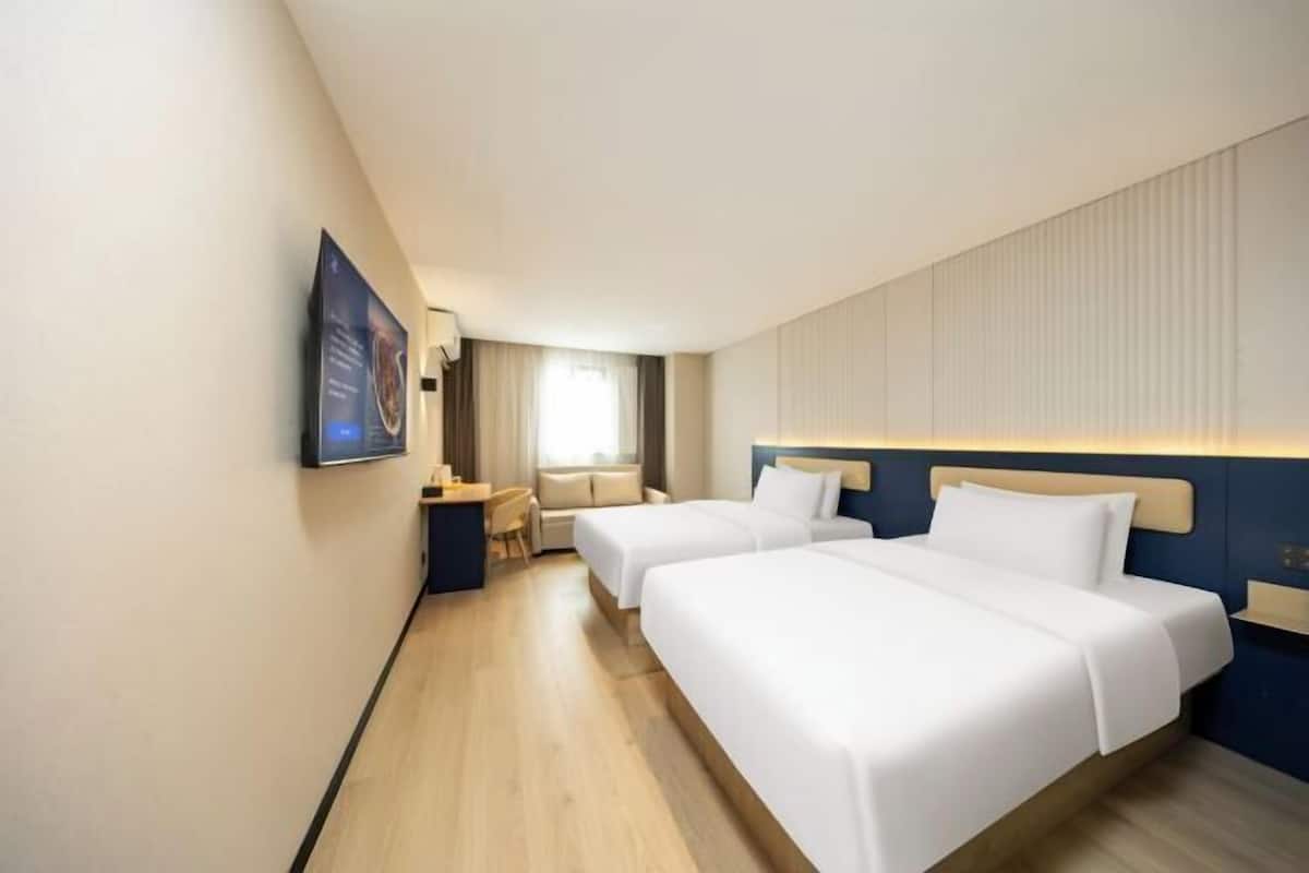 Ein Hotelzimmer mit zwei Betten, einem Schreibtisch und einem Stuhl.