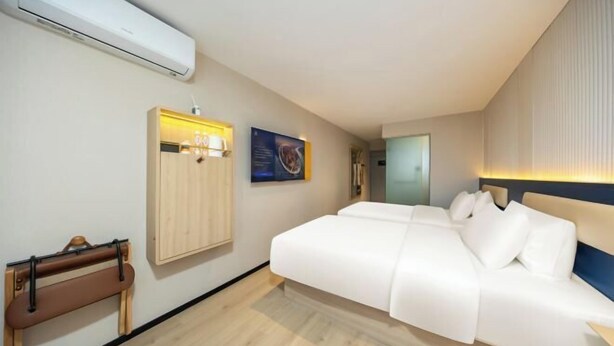 A modern hotel room with a large bed, a wooden cabinet, and a wall-mounted air conditioner. - 7 Days Inn (Beijing South Railway Station Jiaomen West Subway Station Branch) (Beijing)