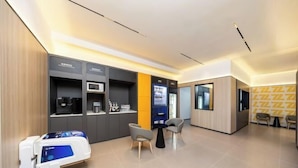 A modern waiting area with a reception desk, seating, a vending machine, and a medical equipment cart. - 7 Days Inn (Beijing South Railway Station Jiaomen West Subway Station Branch) (Beijing)