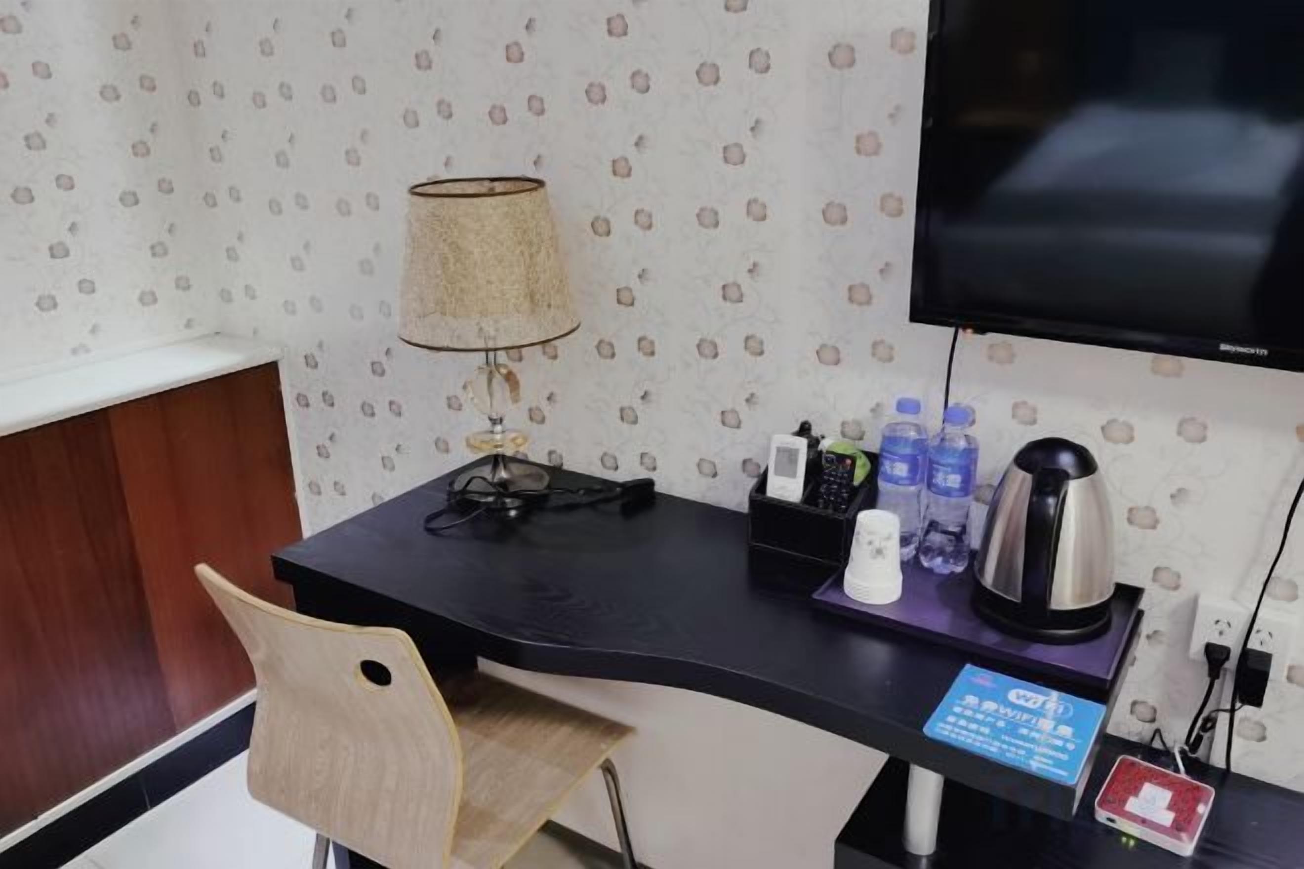 A hotel room with a desk, a lamp, a television, and a coffee maker.