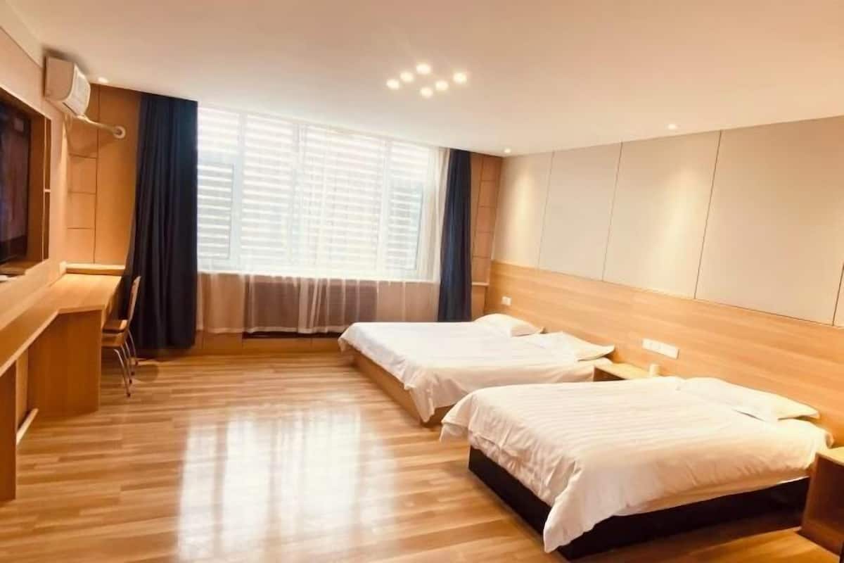 Une chambre d’hôtel avec deux lits, un bureau et une grande fenêtre équipée de stores.