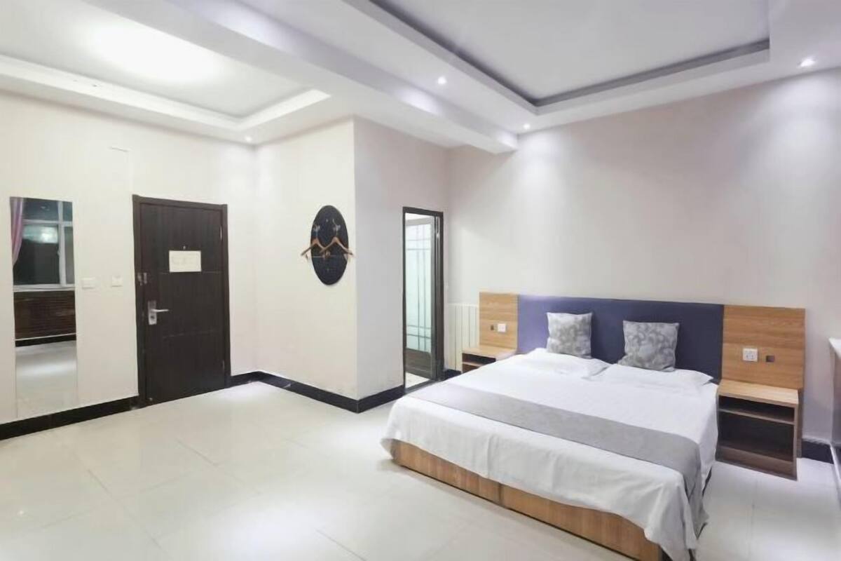 Une chambre d’hôtel moderne avec un grand lit, une armoire et un miroir.