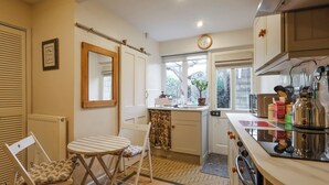 Une cuisine de taille réduite comprenant un coin repas, un radiateur, un miroir et une horloge murale.