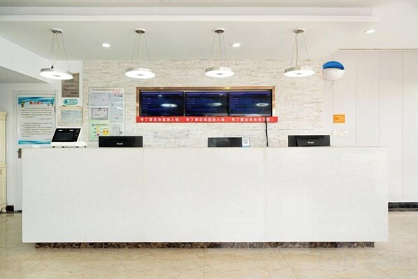 A reception desk with a computer, a digital display, and a wall-mounted information board.