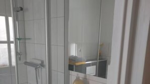A modern bathroom with a glass shower enclosure, a white sink, and a mirror above it. - Vacation apartment no. 2, town center, Randersacker (Randersacker)
