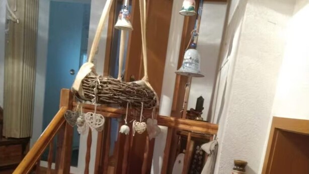 A staircase with a wooden handrail, a white wall with a mirror, and a small table with a lace tablecloth and various decorative items. - Vacation apartment no. 2, town center, Randersacker (Randersacker)