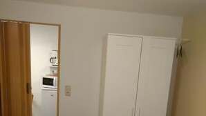 A room with a bed, a desk, a wardrobe, and a kitchenette. - Vacation apartment no. 2, town center, Randersacker (Randersacker)