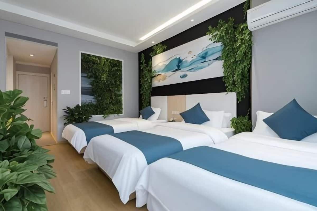 Una habitación de hotel con tres camas, un cuadro grande y plantas verdes.