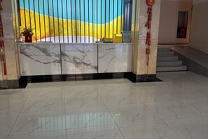 A reception area with a marble counter, a staircase, and a tiled floor. - Yuntianhai Hotel (Jiuzhaigou)