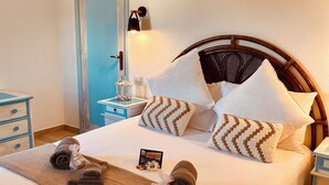 A neatly made bed with a brown towel, a photo, and a small decorative item on the bed. - Bright penthouse in Costa Rei - Sea view and relaxing atmosphere (Costa Rei)