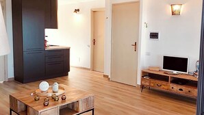 A spacious living room with a wooden coffee table, dark cabinets, a TV stand, and a door leading to another room. - Bright penthouse in Costa Rei - Sea view and relaxing atmosphere (Costa Rei)