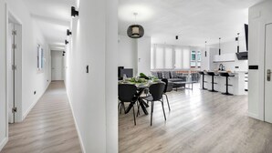 Une cuisine moderne dotée d’un îlot central, de tabourets de bar noirs et d’un coin repas avec une table et des chaises.