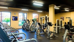 Un gimnasio con cintas de correr, elípticas y equipo de pesas.