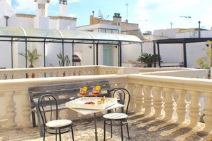 Une terrasse avec une table dressée pour deux personnes, deux chaises et un banc.