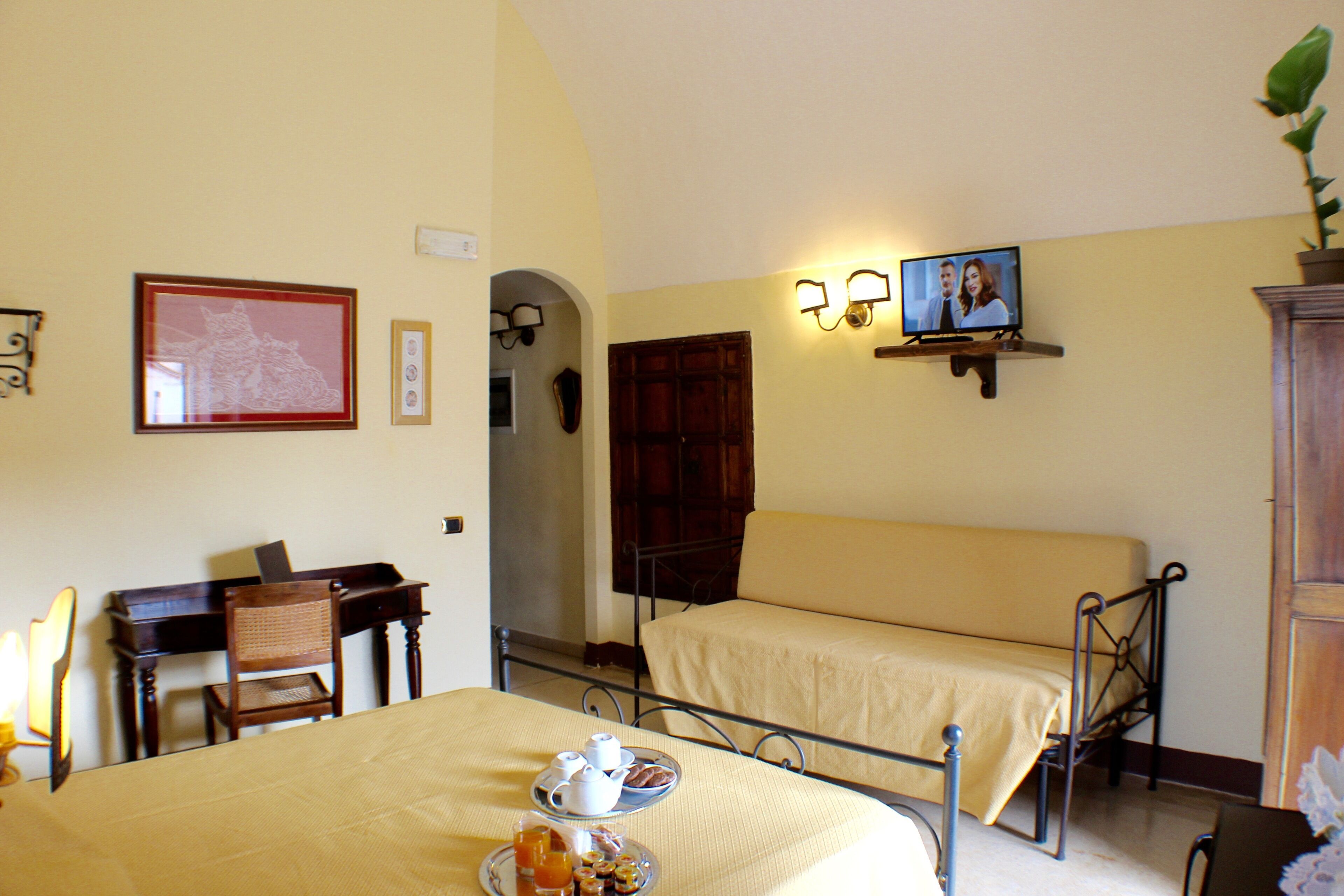 Une chambre d’hôtel comprenant un lit, un bureau avec une chaise, une table où le petit-déjeuner est servi, et un téléviseur.