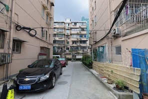 A narrow alleyway between buildings with a parked car and a blue license plate.