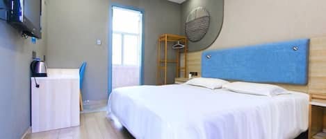 Un dormitorio con cama, escritorio, silla, armario y ventana.
