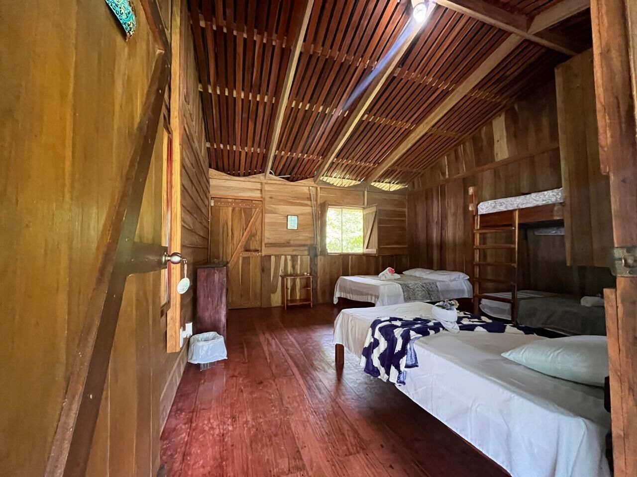 A wooden cabin with two beds, a small table, and a ladder.