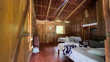 A wooden cabin with two beds, a small table, and a ladder.