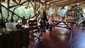 Une structure rustique en bois, avec un sapin de Noël, un espace salon et une table.