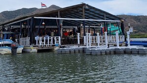 A waterfront restaurant with a covered deck, outdoor seating, and boats docked nearby.