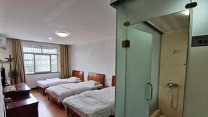 A hotel room with two single beds, a desk, a chair, a window with curtains, and a glass-enclosed shower area. - Feixiang Express Inn (Tongcheng)