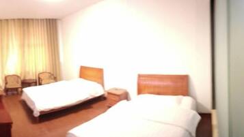 Een hotelkamer met twee bedden, een houten vloer, een tafeltje en een stoel.