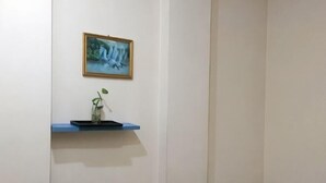 A room with a bed, a shelf with a vase and a plant, and a framed picture on the wall. - Feixiang Express Inn (Tongcheng)