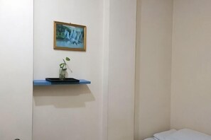 A room with a bed, a shelf with a vase and a plant, and a framed picture on the wall. - Feixiang Express Inn (Tongcheng)