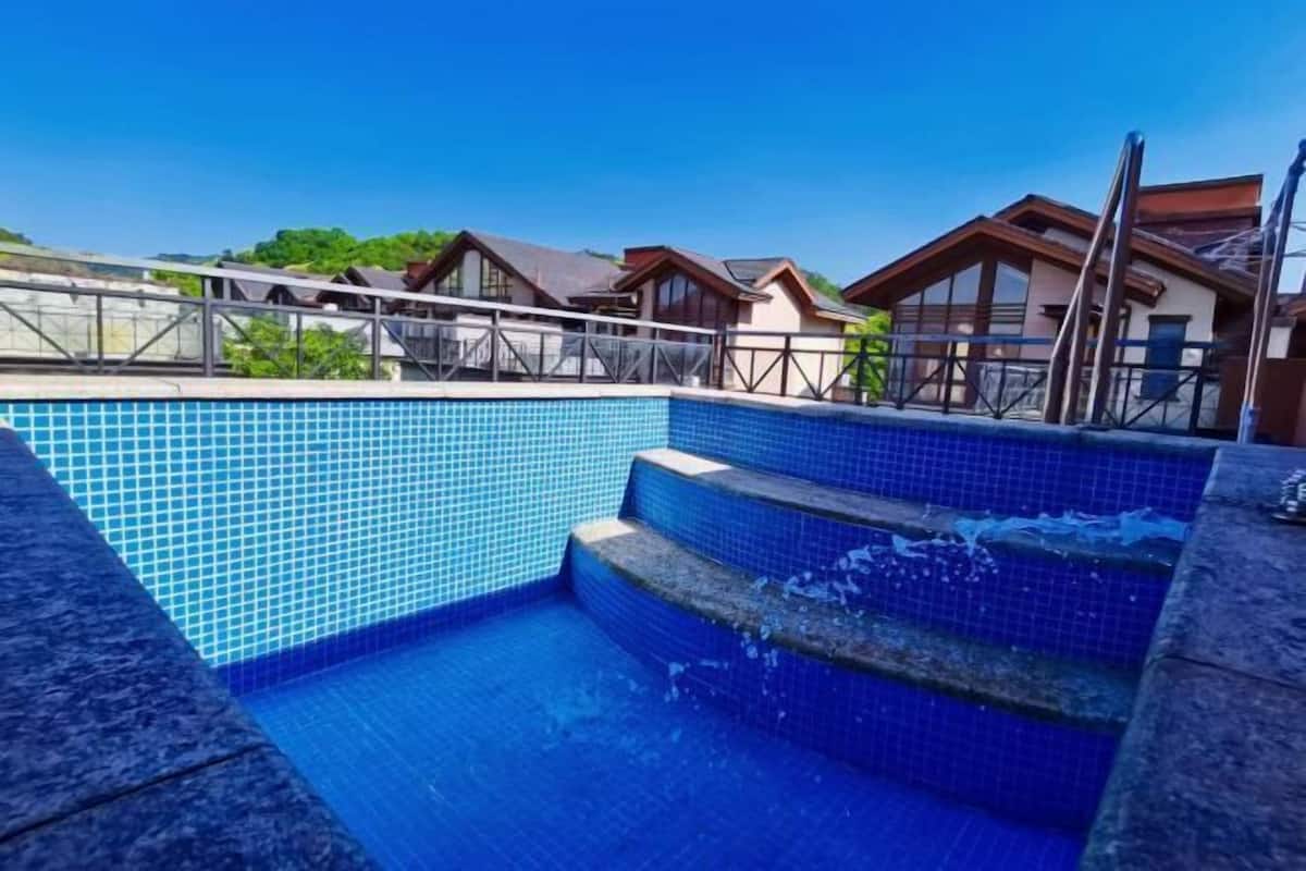 Una piscina amb rajoles blaves, un marc de pedra i escales que hi baixen.