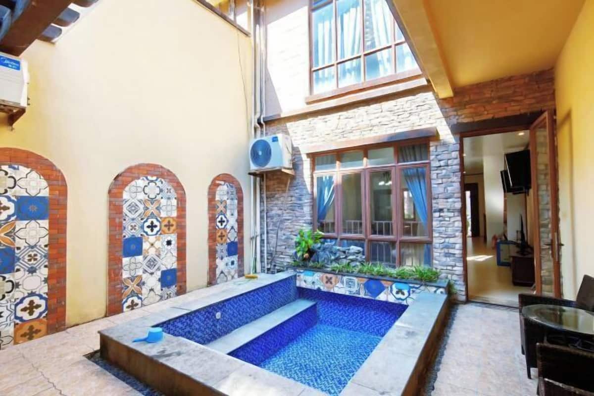 Un pati amb una petita piscina, parets de rajola i una paret de pedra.