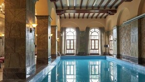 Ein großer, überdachter Swimmingpool mit Steinwänden und Rundbogenfenstern.
