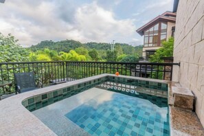 Una piscina con borde de azulejos, rodeada por un muro de piedra y una barandilla de metal.