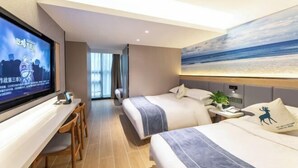 Habitación de hotel con dos camas, televisión, escritorio y un cuadro de una playa.