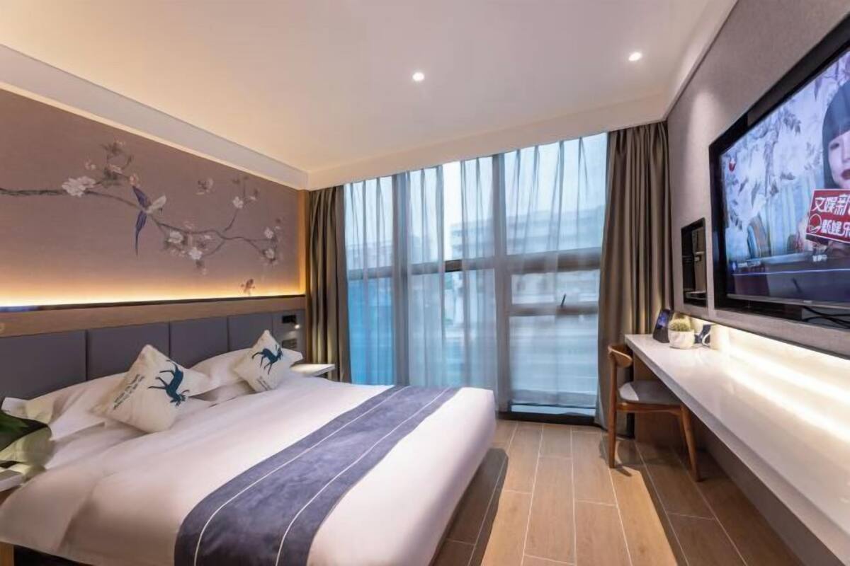 Una camera d'albergo con un letto grande, una televisione a parete e vista sulla città dalla finestra.