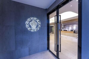 A hotel entrance with a modern design, a logo on the wall, and a reception desk visible through the glass doors. - Four Seasons Fenglin Smart Hotel Shanghai (Shanghai Fudan University Subway Station) (Shanghai)