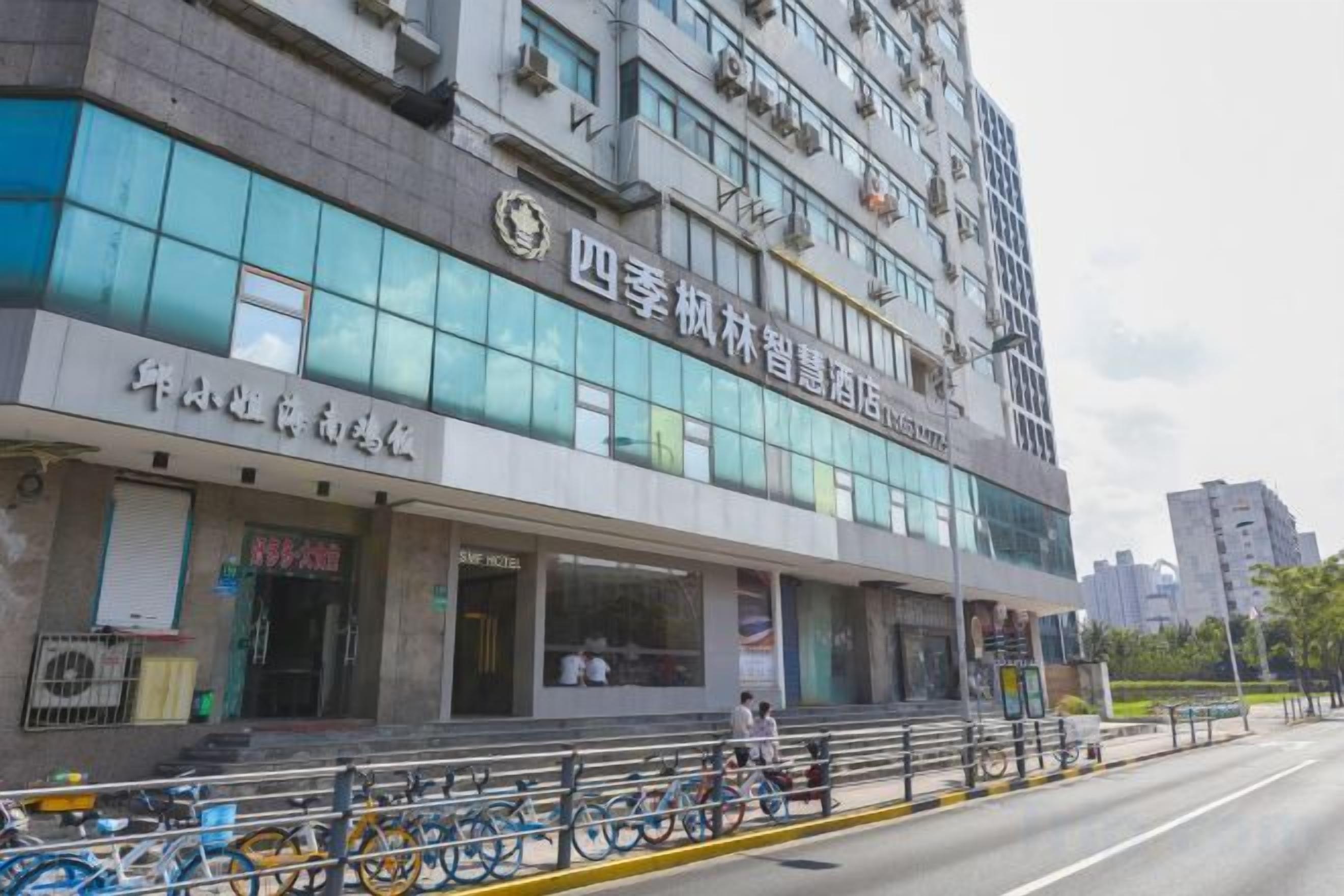 Un edificio de varios pisos con un letrero que indica que es un hotel. Hay bicicletas estacionadas afuera y el edificio presenta un estilo arquitectónico moderno con grandes ventanales.