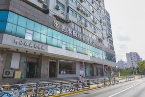 A multi-story building with a sign indicating it is a hotel. There are bicycles parked outside, and the building has a modern architectural style with large windows. - Four Seasons Fenglin Smart Hotel Shanghai (Shanghai Fudan University Subway Station) (Shanghai)