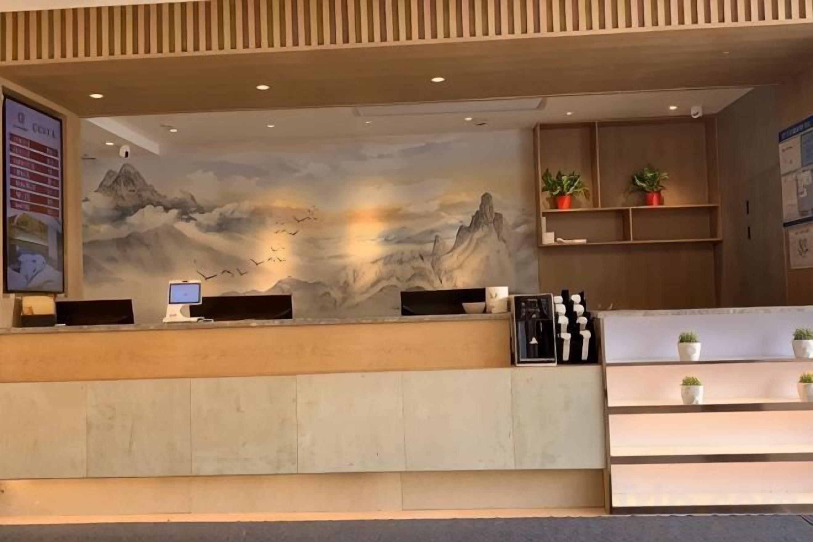 A reception desk with a mural, a computer, and a plant display.