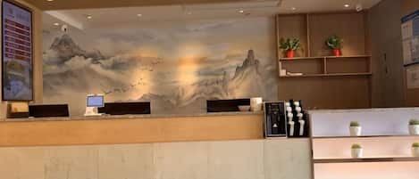 A reception desk with a mural, a computer, and a plant display.