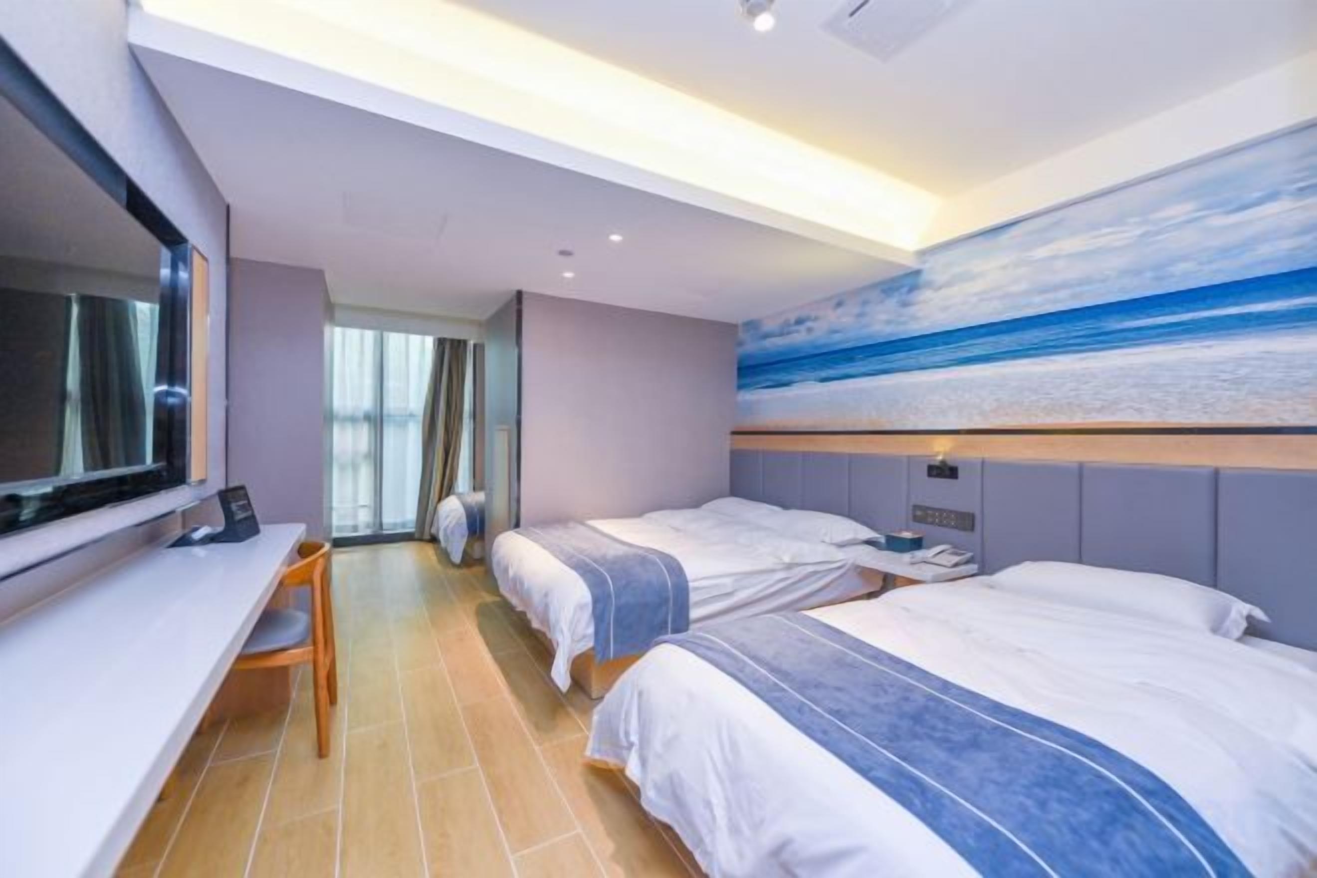 Habitación de hotel con dos camas, un escritorio, un televisor y un cuadro de una escena de playa.