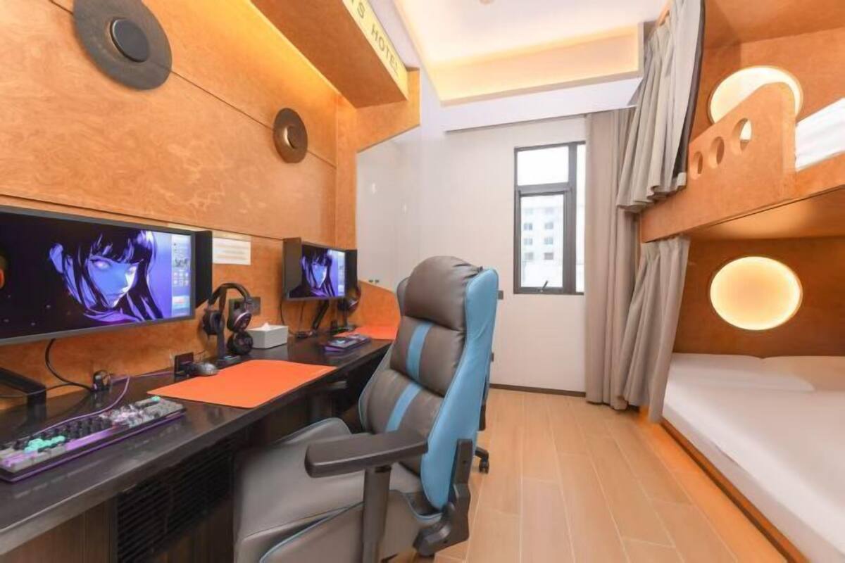 Una stanza con un letto a castello, due monitor, una sedia da gaming e una scrivania con tastiera e mouse.